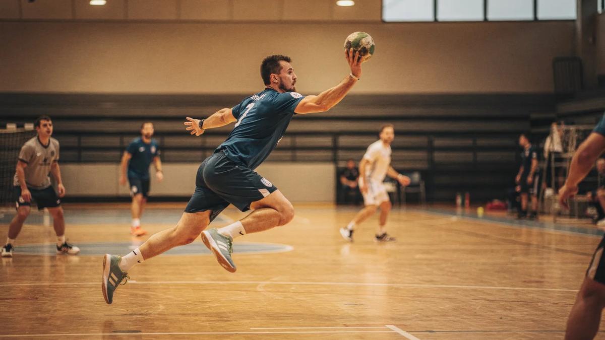 Joueur de handball en suspension au moment du tir dans un gymnase, mouvement figé